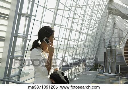Stock Photography - Businesswoman talking on cell phone in airport. Fotosearch