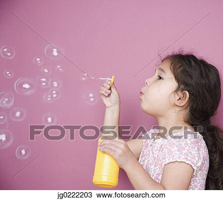 Stock Image - Girl blowing bubbles with wand. Fotosearch