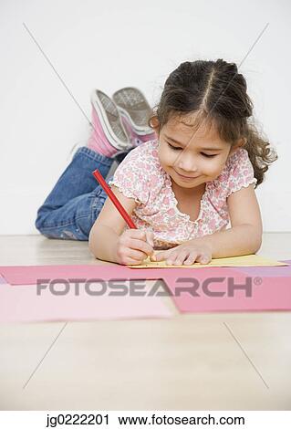 Girl coloring while laying on floor View Large Photo Image Stock Image - Girl coloring while laying on floor. Fotosearch
