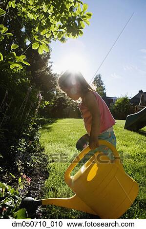 Stock Image - Girl watering plants with watering can. Fotosearch