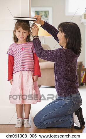 Stock Photograph - Mother measuring daughter's height. Fotosearch