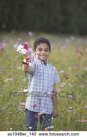 Portrait of boy holding bouquet of flowers in field View Large Photo Image Stock Image - Portrait of boy holding bouquet of flowers in field. Fotosearch