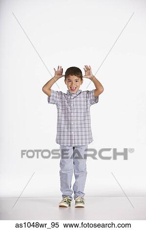 Stock Photography - Portrait of boy sticking tongue out and gesturing with hands. Fotosearch