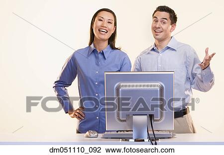 Stock Image - Portrait of businesspeople laughing at computer. Fotosearch