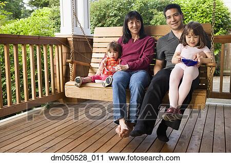 Stock Image - Portrait of family on porch swing. Fotosearch