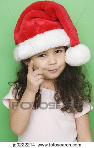 Picture - Portrait of girl wearing santa hat and pointing. Fotosearch