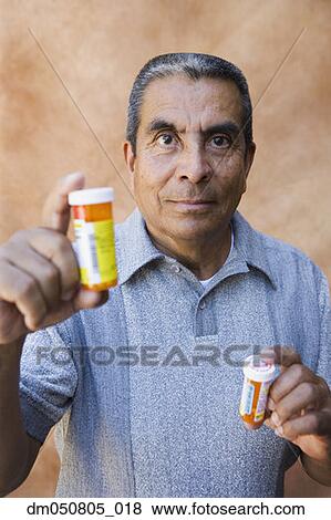 Portrait of man holding medication bottles View Large Photo Image Stock Photo - Portrait of man holding medication bottles. Fotosearch