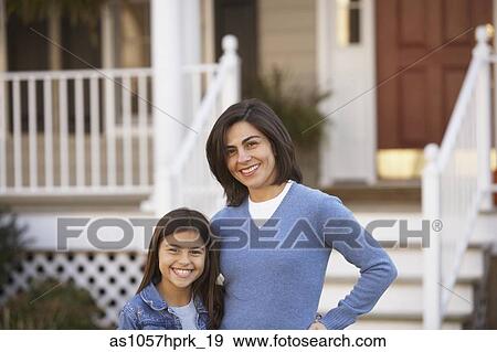 Stock Photo - Portrait of mother and daughter in front of house. Fotosearch