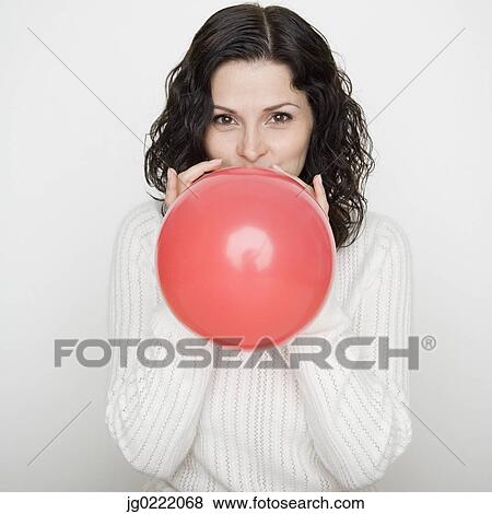 Stock Photo - Portrait of woman blowing up balloon. Fotosearch