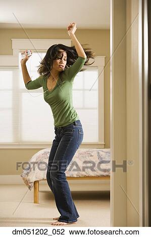 Stock Image - Woman dancing in bedroom while listening to music. Fotosearch