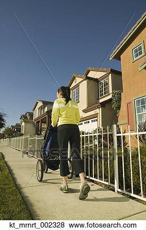 Woman walking down sidewalk with stroller View Large Photo Image Stock Photo - Woman walking down sidewalk with stroller. Fotosearch