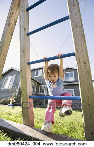 Picture - Young girl playing on play structure in back yard. Fotosearch