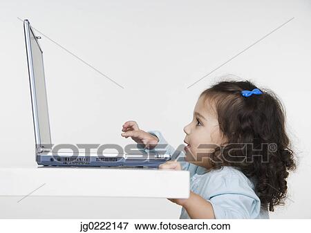 Stock Photo - Young girl playing with laptop computer. Fotosearch