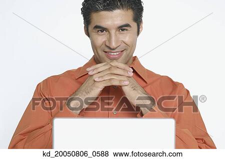 Stock Photo - Young man smiling for the camera while using a laptop. Fotosearch