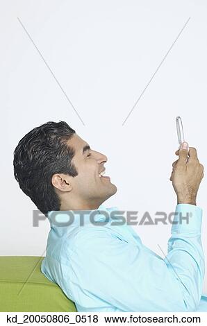 Young man using his cell phone View Large Photo Image Stock Photo - Young man using his cell phone. Fotosearch