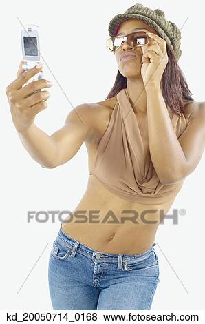Stock Photo - Young woman taking a picture of herself with her camera phone. Fotosearch