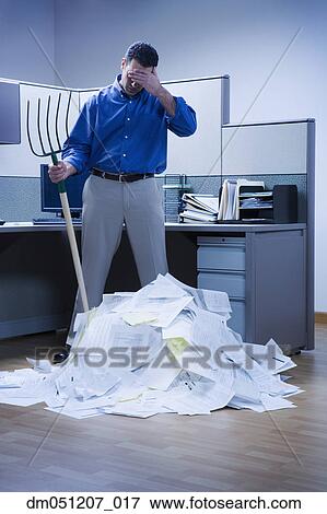 Businessman overlooking mountain of paper and holding rake View Large Photo Image Stock Photo - Businessman overlooking mountain of paper and holding rake. Fotosearch