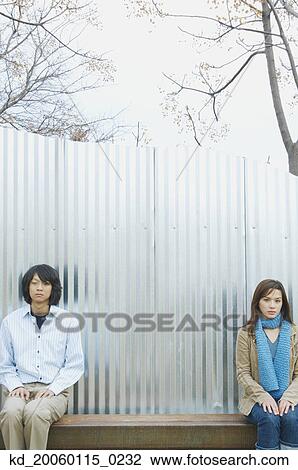 Stock Image - Couple sitting as far away from each other as possible. Fotosearch