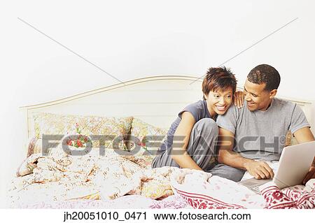Couple using a laptop in bed View Large Photo Image Stock Image - Couple using a laptop in bed. Fotosearch