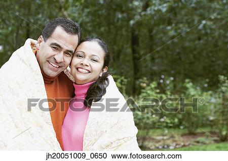 Stock Image - Couple wrapped in a blanket outdoors. Fotosearch