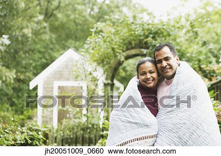 Stock Image - Couple wrapped in a blanket outdoors. Fotosearch