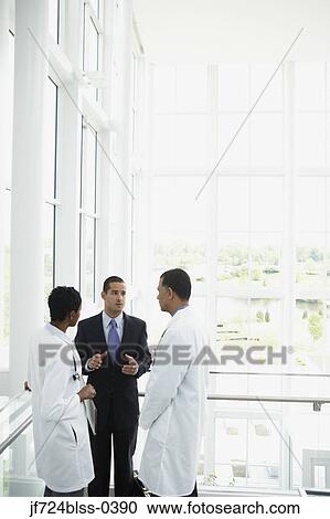 Stock Image - Doctors talking to businessman. Fotosearch