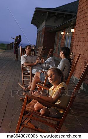 Family sitting in wooden rocking chairs at dusk View Large Photo Image Stock Photography - Family sitting in wooden rocking chairs at dusk. Fotosearch
