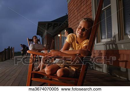 Stock Photography - Family sitting in wooden rocking chairs at dusk. Fotosearch