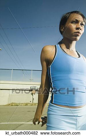 Stock Image - Female athlete stretching in urban surroundings. Fotosearch