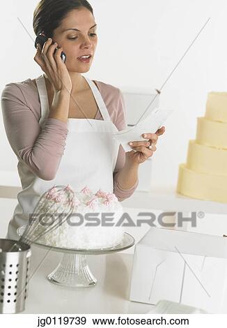Stock Photo - Female baker talking on her cell phone. Fotosearch