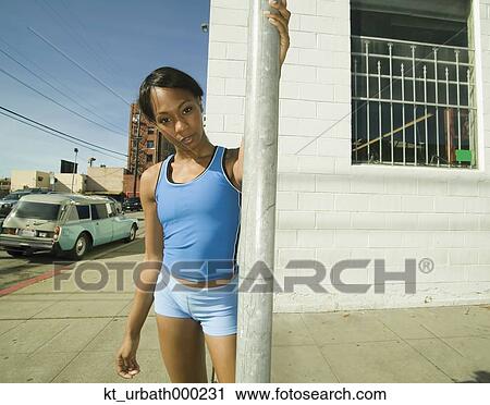 Stock Image - Female jogger resting on street corner. Fotosearch