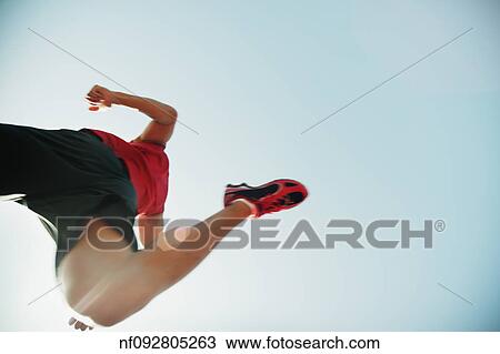Stock Image - Low angle view of male athlete running. Fotosearch