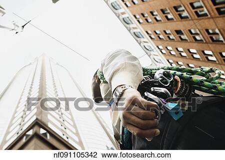 Stock Image - Low angle view of rock climber in urban setting. Fotosearch