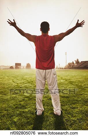 Stock Photograph - Male athlete holding his arms out on football field. Fotosearch