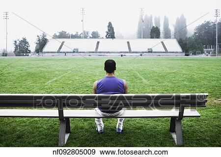Stock Photo - Male athlete sitting on bench. Fotosearch