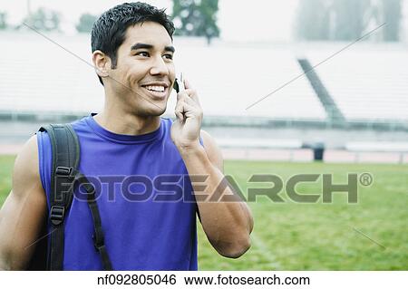 Male athlete talking on his cell phone in football field View Large Photo Image Stock Photograph - Male athlete talking on his cell phone in football field. Fotosearch