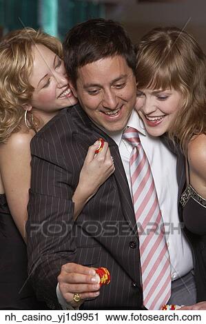 Stock Image - Man gambling as women fawn over him. Fotosearch