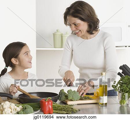 Picture - Mother and daughter cooking together. Fotosearch