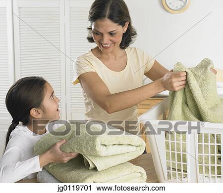 Stock Image - Mother and daughter folding laundry together. Fotosearch