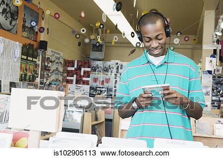 Teenage boy listening to headphones in a music store View Large Photo Image Stock Image - Teenage boy listening to headphones in a music store. Fotosearch