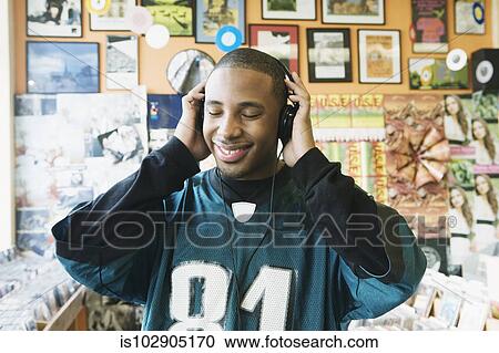 Teenage boy listening to headphones in a music store View Large Photo Image Stock Image - Teenage boy listening to headphones in a music store. Fotosearch