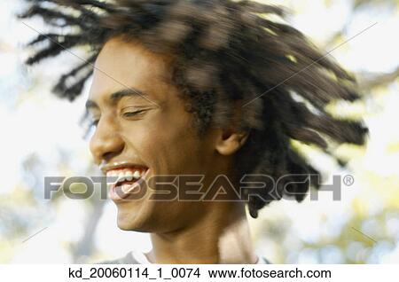 Picture - Teenage boy tossing his dreadlocks. Fotosearch