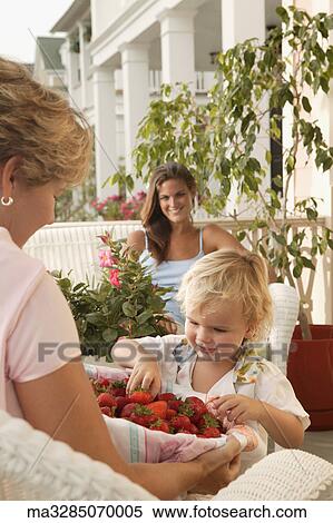 Woman offering strawberries to young child View Large Photo Image Stock Photography - Woman offering strawberries to young child. Fotosearch