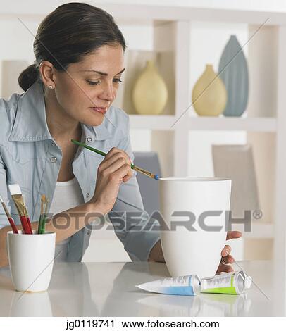 Stock Image - Woman painting a vase. Fotosearch