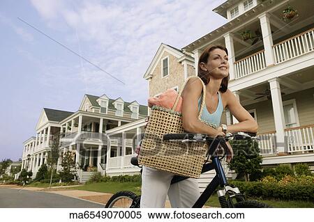 Woman riding a bike down suburban street View Large Photo Image Stock Photography - Woman riding a bike down suburban street. Fotosearch