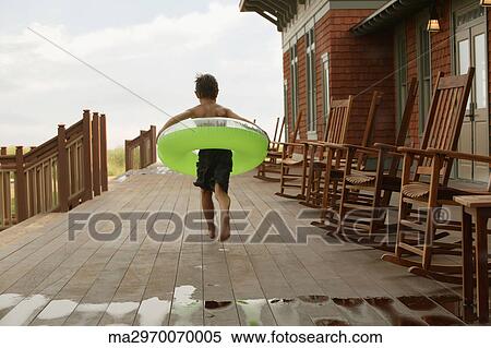 Stock Photography - Young boy wearing inner tube on wooden deck. Fotosearch