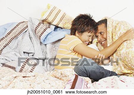 Stock Image - Young couple relaxing among blankets. Fotosearch