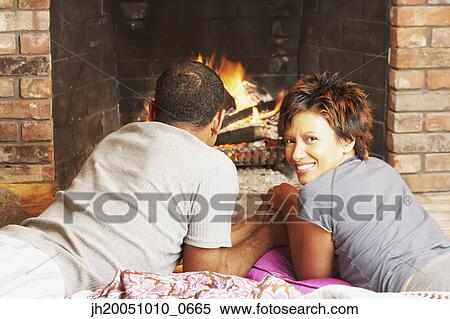 Young couple relaxing in front of a fire View Large Photo Image Stock Photography - Young couple relaxing in front of a fire. Fotosearch