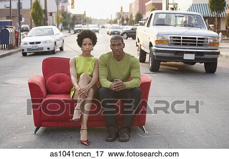 Stock Photo - Young couple sitting on a couch outdoors. Fotosearch