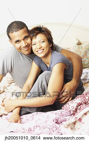 Young couple smiling for the camera in bed View Large Photo Image Picture - Young couple smiling for the camera in bed. Fotosearch